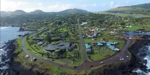 Vista aérea de un pueblo costero en Isla de Pascua con edificios y naturaleza exuberante.