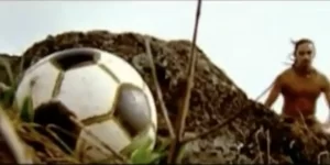 Escena de fútbol en la Isla de Pascua con un balón y un jugador en el fondo.