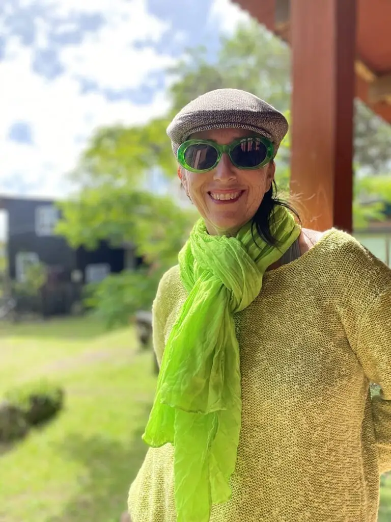 Mujer con bufanda verde y gafas de sol, sonriendo.