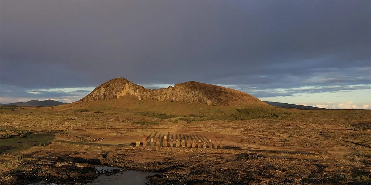 Paisaje de la Isla de Pascua con colina y estatuas Moái al amanecer.